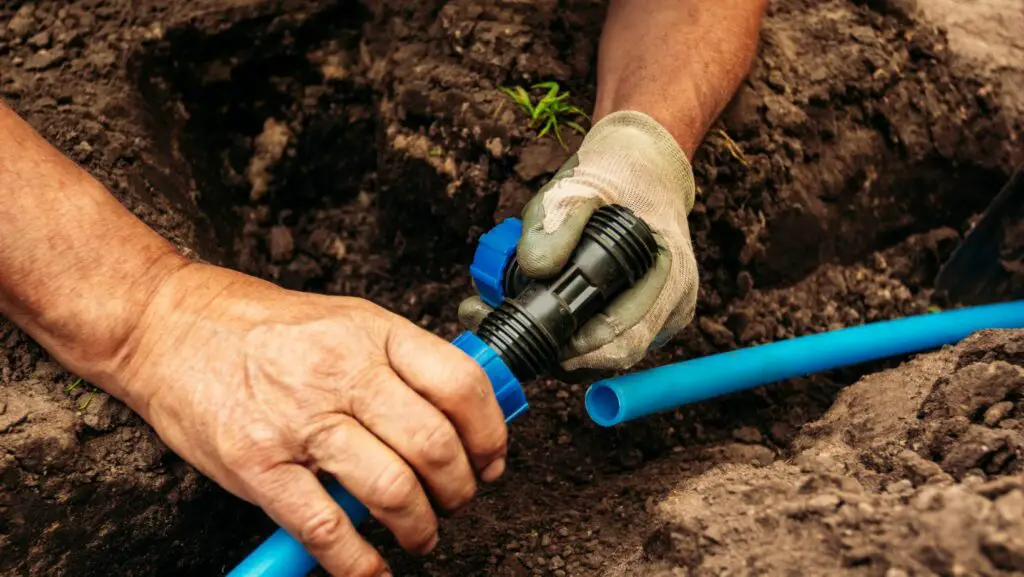 A man repairing a drainage system in a garden
